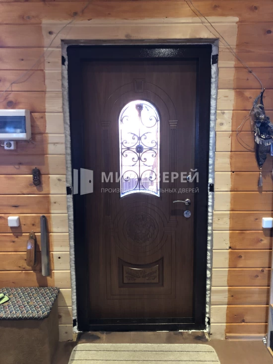 Коричневая дверь с ковкой для загородного дома - фото